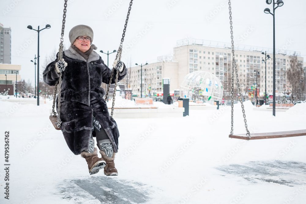 An elderly woman goes for a drive on a swing.