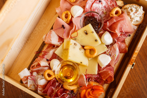 Tagliere di salumi e formaggi con miele, taralli e salse servito in un elegante cassetta di legno photo