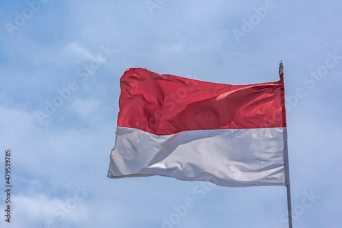 Indonesian red and white national flag rising and under the clear and bright blue sky