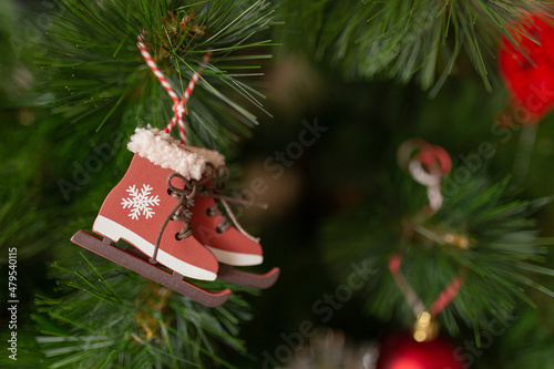 A Christmas toy in the form of skates hangs on a branch of a Christmas tree. Abstract new year card