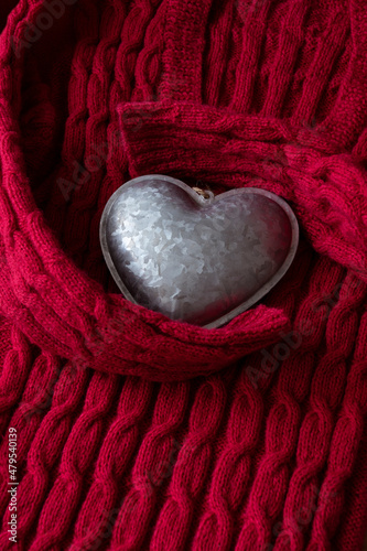 Red cable knitted sweater hugging silver metal textured heart
