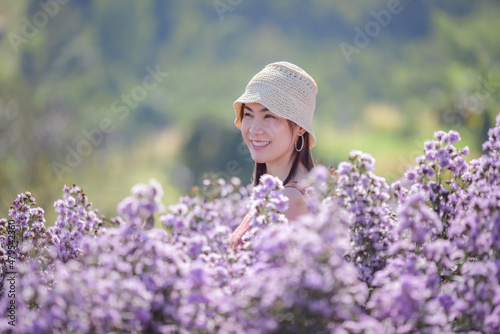 Young happy traveler Asian woman sightseeing on Margaret Aster flowers field in garden at Khao Kho, Thailand, relaxing on vacation concept