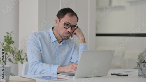 Middle Aged Man Falling Asleep while using Laptop in Office, Nap