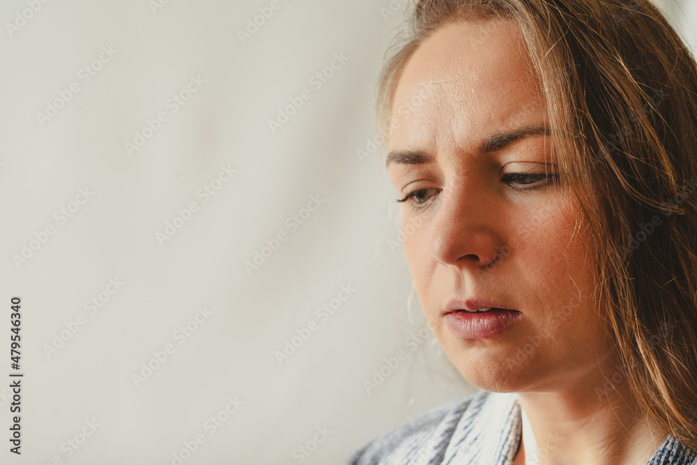 Concerned young white woman looking down against white background Concerned young white woman looking down against white background