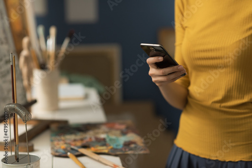 Artist working in the studio and chatting with her phone