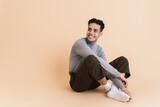 Young middle eastern man smiling while sitting on floor