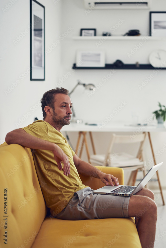 Man working on a laptop from the living room. Work from home concept. Man working on a laptop from the living room. Work from home concept.