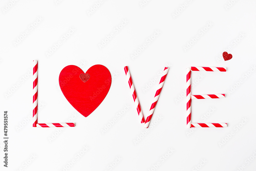Love word made from striped red and white drinking straws and red heart on white background