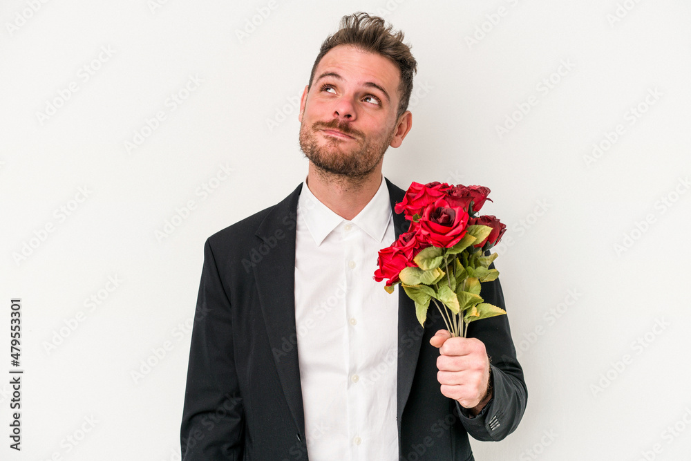 Young caucasian man holding bouquet of flowers isolated on white background dreaming of achieving goals and purposes Young caucasian man holding bouquet of flowers isolated on white background dreaming of achieving goals and purposes