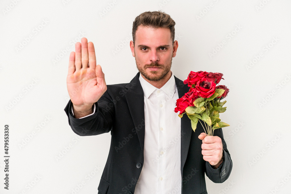 Young caucasian man holding bouquet of flowers isolated on white background standing with outstretched hand showing stop sign, preventing you. Young caucasian man holding bouquet of flowers isolated on white background standing with outstretched hand showing stop sign, preventing you.