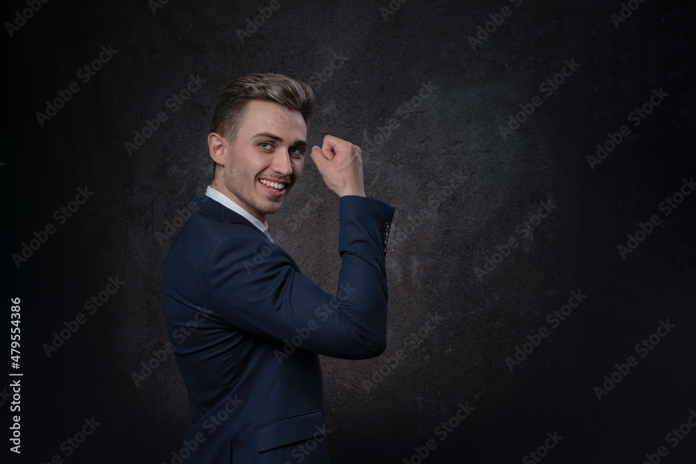 Emotional young business man in suit and tie celebrating victory with body gesture and whoop yes. On a black background . Copy space on right