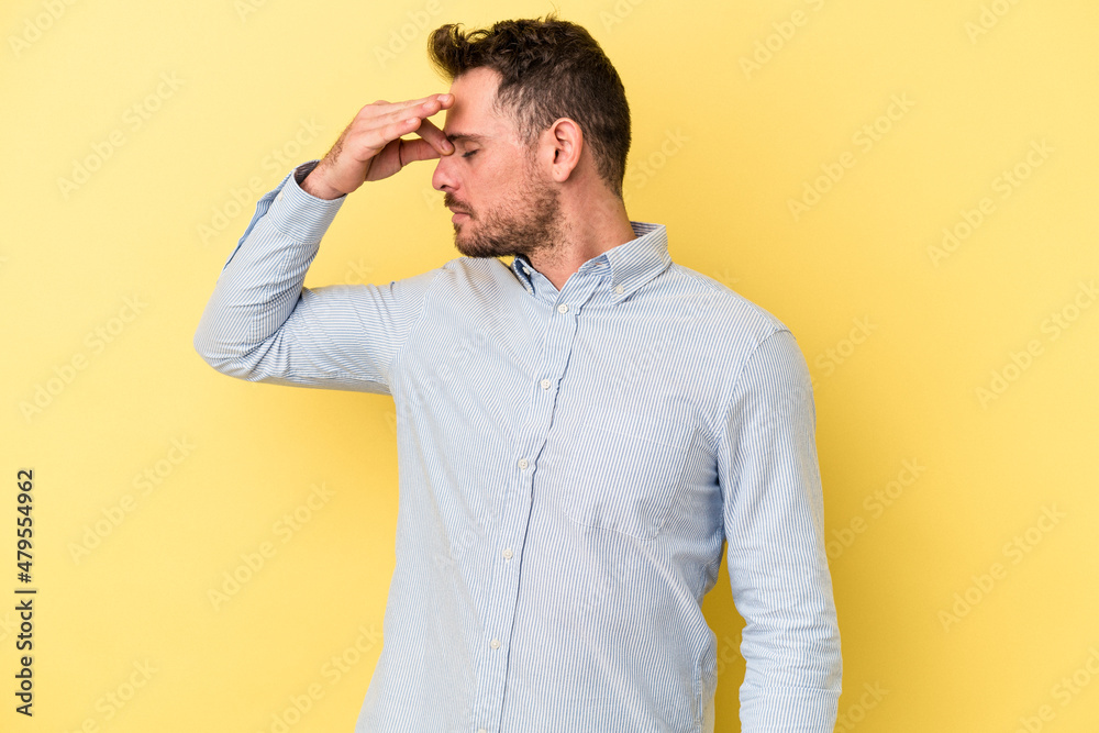 Young caucasian man isolated on yellow background having a head ache, touching front of the face.