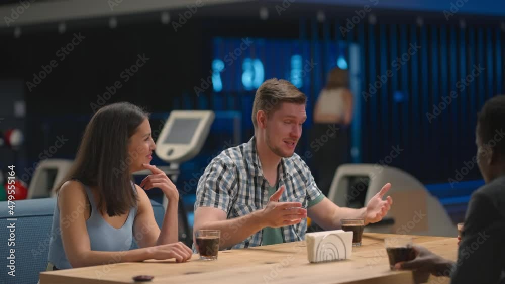 A multi ethnic group of friends in a bowling club are chatting at the table and smiling A multi ethnic group of friends in a bowling club are chatting at the table and smiling