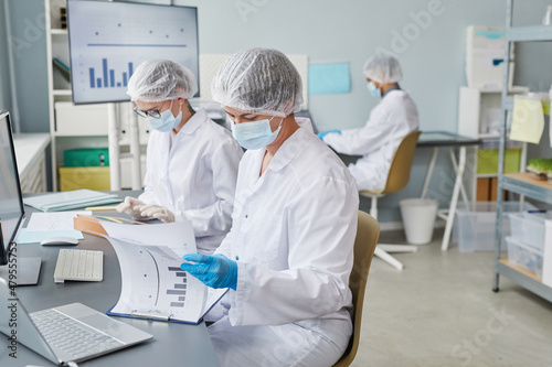 Group of scientists sitting at the table and working with statistics during pandemic in the laboratory