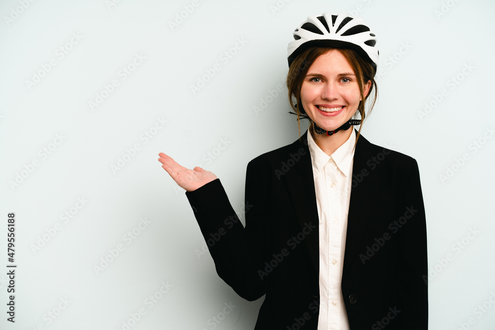 Young business English woman isolated on blue background showing a copy space on a palm and holding another hand on waist. Young business English woman isolated on blue background showing a copy space on a palm and holding another hand on waist.