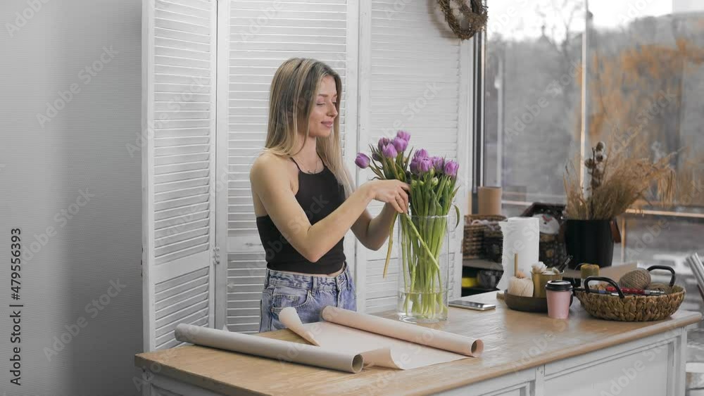 A young beautiful woman engaged in floristry begins to collect the best flowers for her flower arrangement. Floristry A young beautiful woman engaged in floristry begins to collect the best flowers for her flower arrangement. Floristry