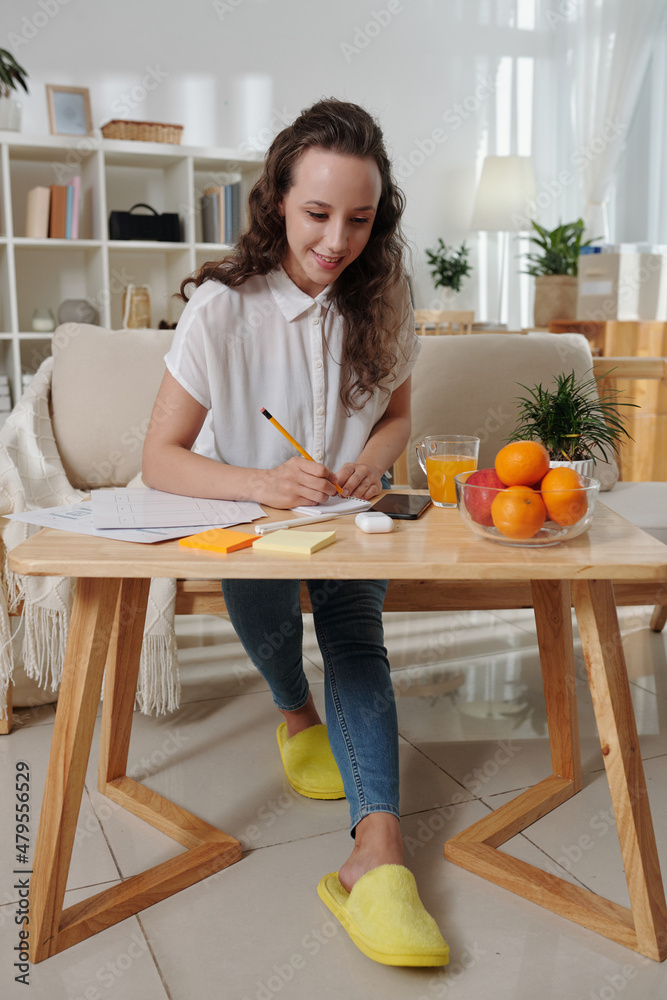 Smiling young project manager working from home, writing down ideas, working with documents and answering text messages Smiling young project manager working from home, writing down ideas, working with documents and answering text messages