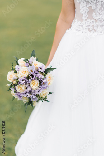 The bride's wedding bouquet of milk roses and lilac eustoms in the hands of the bride close-up