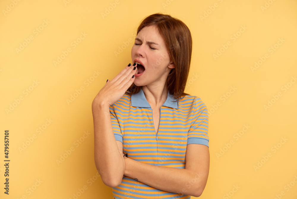 Young English woman isolated on yellow background yawning showing a tired gesture covering mouth with hand. Young English woman isolated on yellow background yawning showing a tired gesture covering mouth with hand.