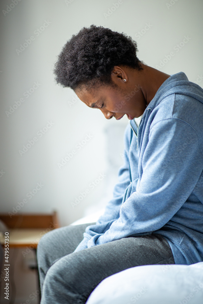 young African American woman siting on side of bed and yawning young African American woman siting on side of bed and yawning