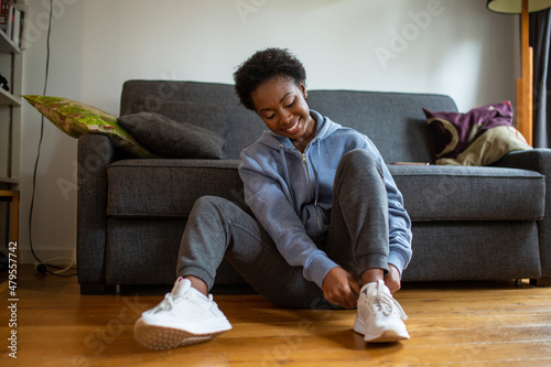Photography young African American woman siting on floor and putting on shoes