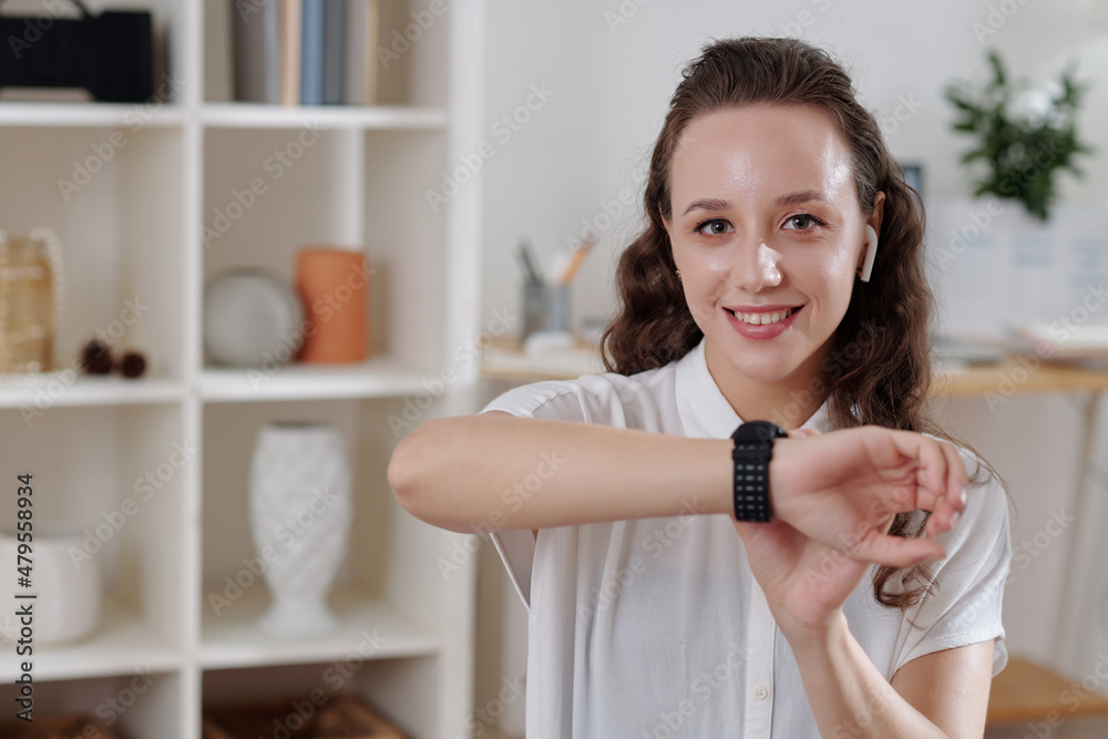 Portrait of happy young woman setting alarm on smartwatch not to miss her business meeting Portrait of happy young woman setting alarm on smartwatch not to miss her business meeting