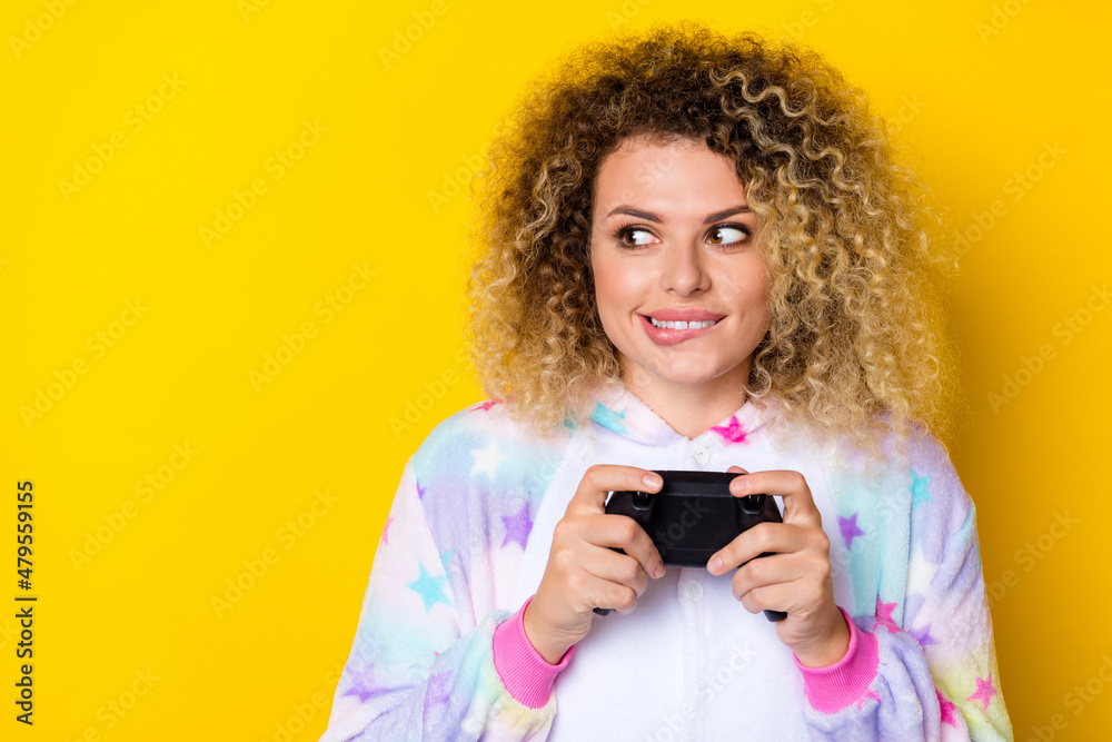 Portrait of attractive cheery sly wavy-haired girl in pajama playing console copy space isolated over bright yellow color background Portrait of attractive cheery sly wavy-haired girl in pajama playing console copy space isolated over bright yellow color background