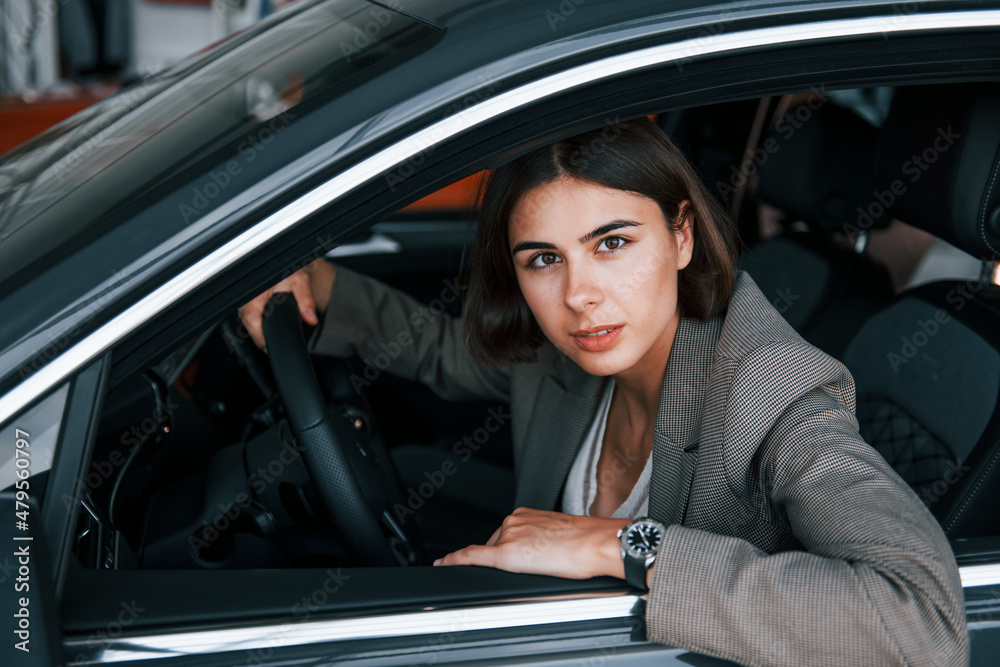 Woman testing new car. Sitting indoors in modern automobile