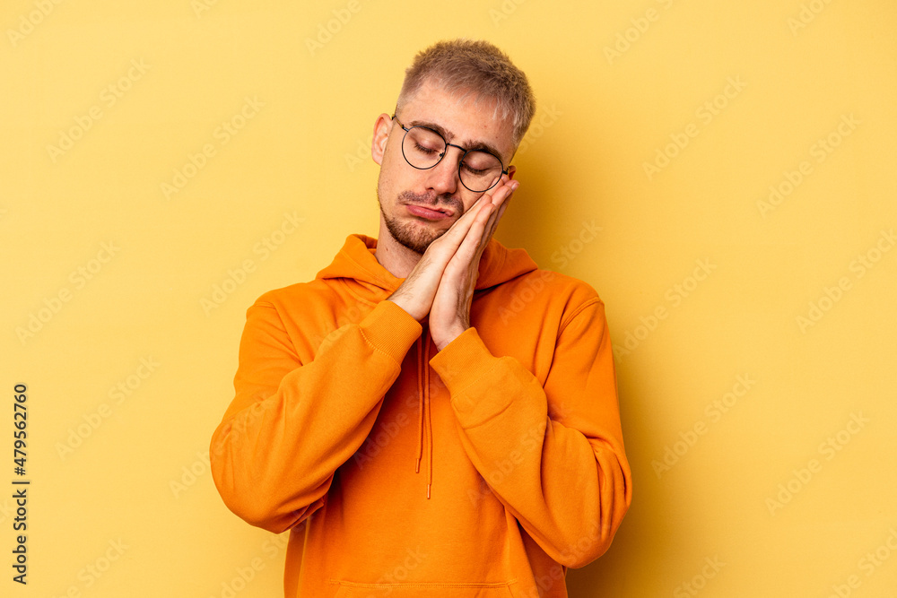 Young caucasian man isolated on yellow background yawning showing a tired gesture covering mouth with hand. Young caucasian man isolated on yellow background yawning showing a tired gesture covering mouth with hand.