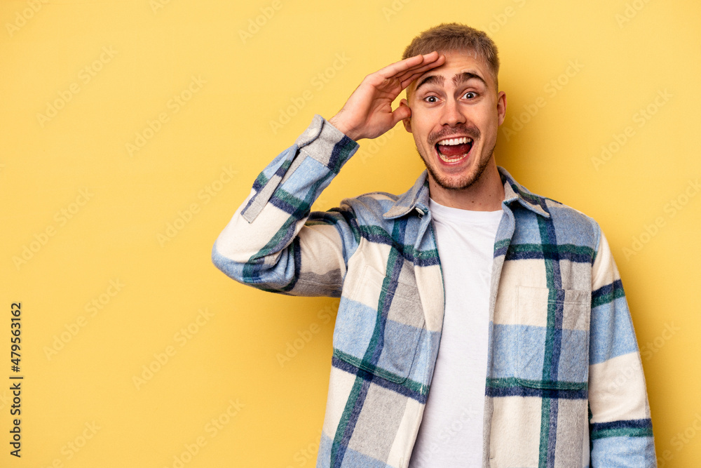 Young caucasian man isolated on yellow background shouts loud, keeps eyes opened and hands tense. Young caucasian man isolated on yellow background shouts loud, keeps eyes opened and hands tense.