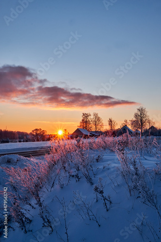 sunset in cold winter morning in country side with snow and grass in foreground