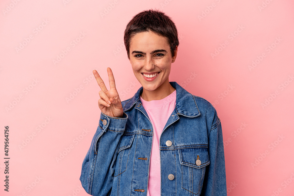 Young caucasian woman isolated on blue background showing victory sign and smiling broadly. Young caucasian woman isolated on blue background showing victory sign and smiling broadly.