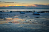 deep snow over rocks at the beach in cold winter sunset by the sea