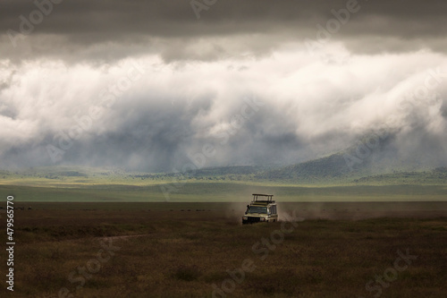 Safari car on a road in Ngorongoro National Park, Tanzania with beautiful clouds in background. Wild nature of Africa. © danmir12
