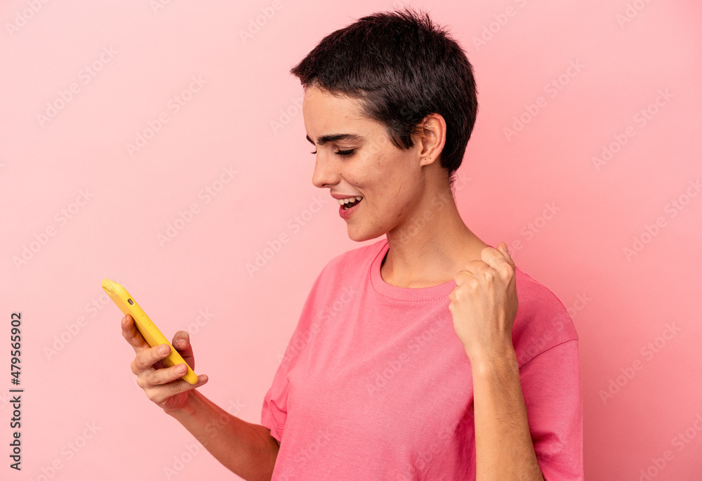 Young caucasian woman holding mobile phone isolated on pink background