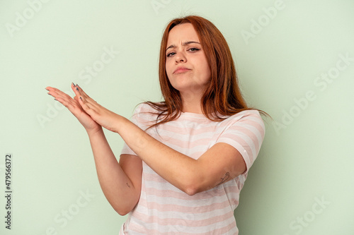 Young caucasian woman isolated on green background feeling energetic and comfortable, rubbing hands confident.