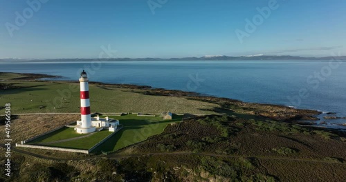 an aerial view of tarbat ness lighthouse on easter ross in the highlands of scotland near inverness showing blue sky and calm seas with the lighthouse dominating the scene and rocks photo