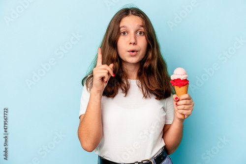 Little caucasian girl eating an ice cream isolated on blue background having some great idea, concept of creativity.