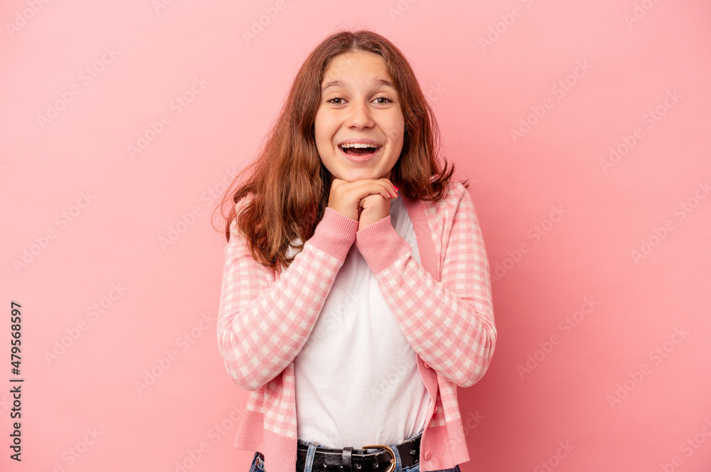 Little caucasian girl isolated on pink background praying for luck, amazed and opening mouth looking to front.