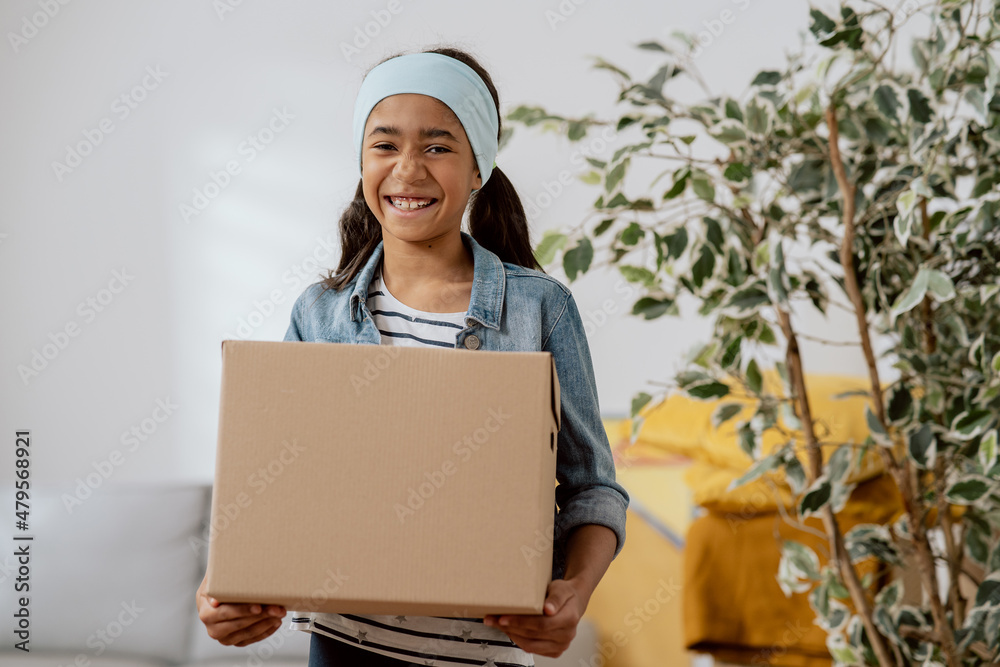Sweet girl helps her parents during the move, carries things from room packed in cardboard box, carries boxes, moving in, renting an apartment, house Sweet girl helps her parents during the move, carries things from room packed in cardboard box, carries boxes, moving in, renting an apartment, house
