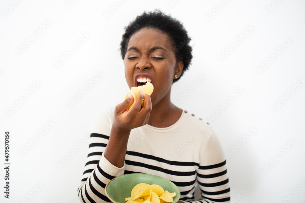 hungry African American woman eating chips by isolated white background hungry African American woman eating chips by isolated white background