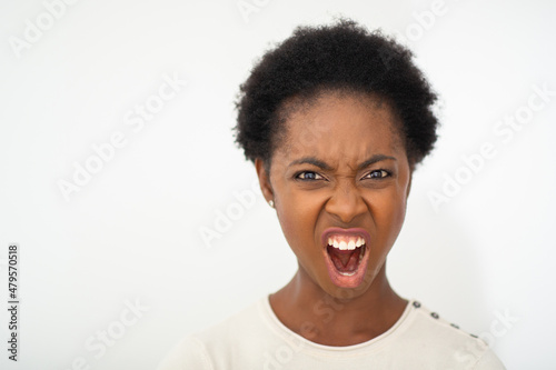 Close up young African American woman shouting with mouth open by white isolated background