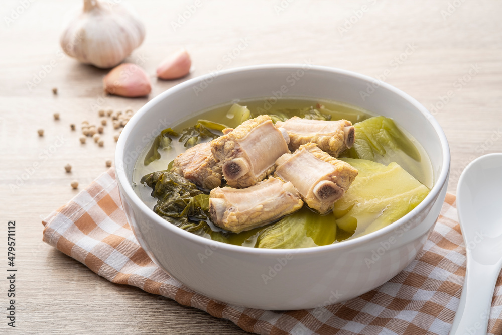 Pickled lettuce soup with pork spare ribs in white bowl Pickled lettuce soup with pork spare ribs in white bowl