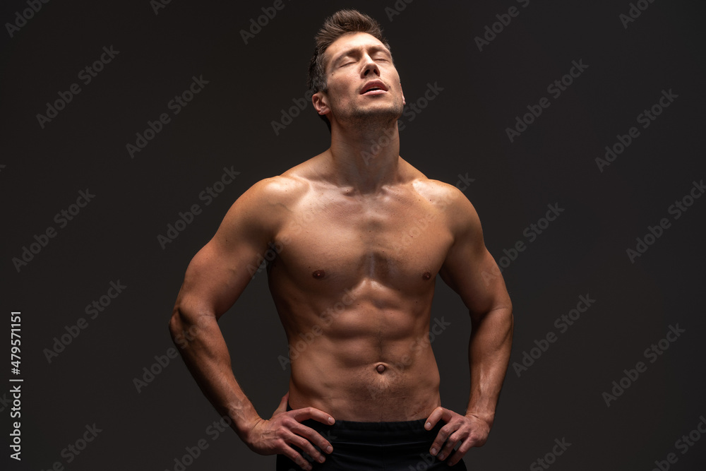 Bodybuilder posing on black background. Beautiful sporty guy male power. Fitness muscled man standing at the studio