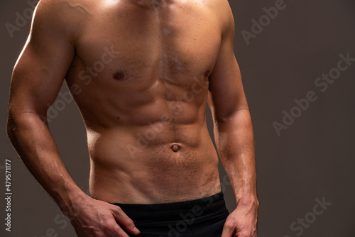 Close up view of the young handsome male athlete showing muscles isolated on a dark background. Sport and bodybuilding concept