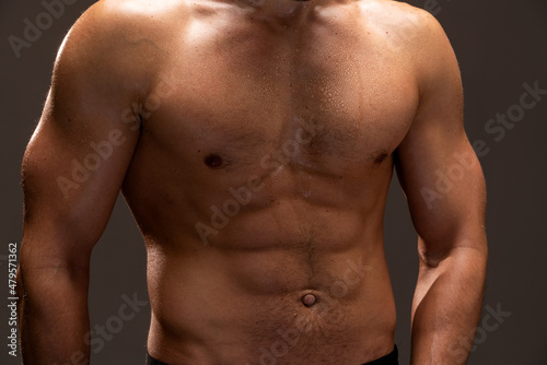 Close up view of the bodybuilder with perfect abs posing on black background. Beautiful sporty guy male power. Fitness muscled man standing at the studio