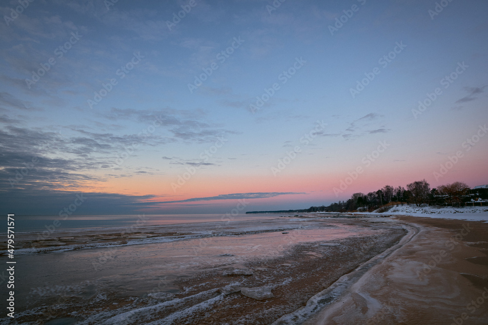 sunset in the winter at the beach with frozen sea