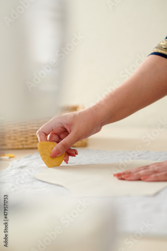 Hands of seamstress using chalk when marking out sewing pattern on fabric