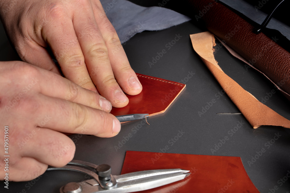 Obraz premium The process of making leather goods. The hands of the master work with a leather product.