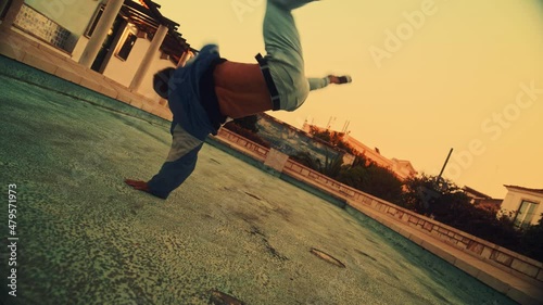 Activel Young Latin Man in Stylish Clothes Actively Breakdancing, Spinning on Hands on the Street of an Old Town in a City. Scene Shot in an Urban Environment in Ancient Cultural Tourist Location. photo